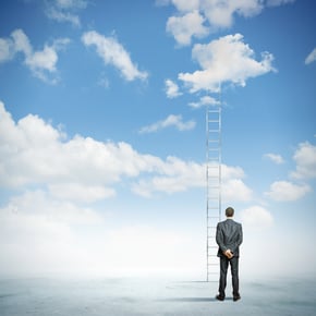 Rear view of businessman standing near ladder going high in sky.jpeg